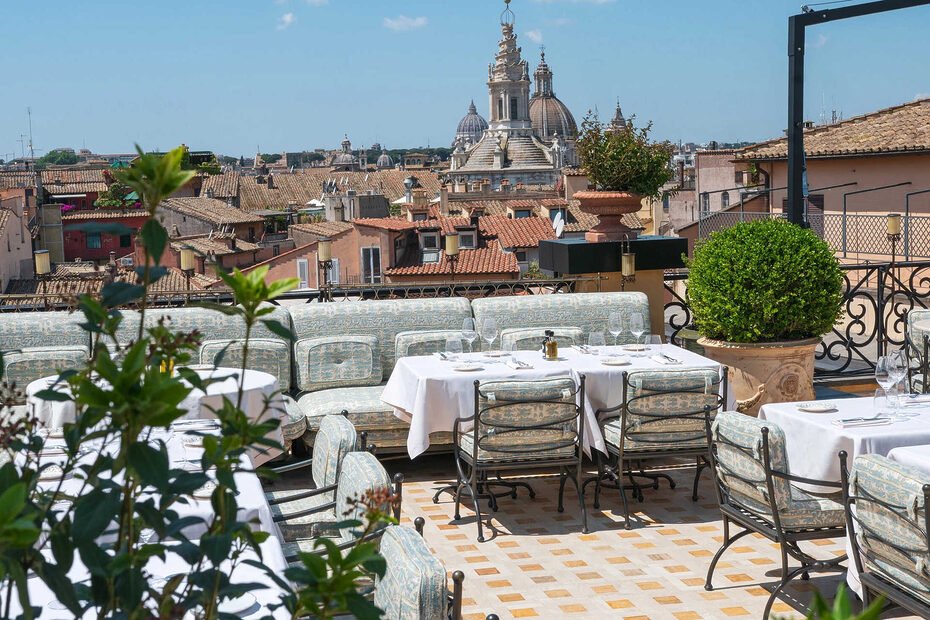 Luxurious rooftop lounge bar with plush seating, overlooking the iconic Pantheon dome and Roman cityscape at Orient Express La Minerva.